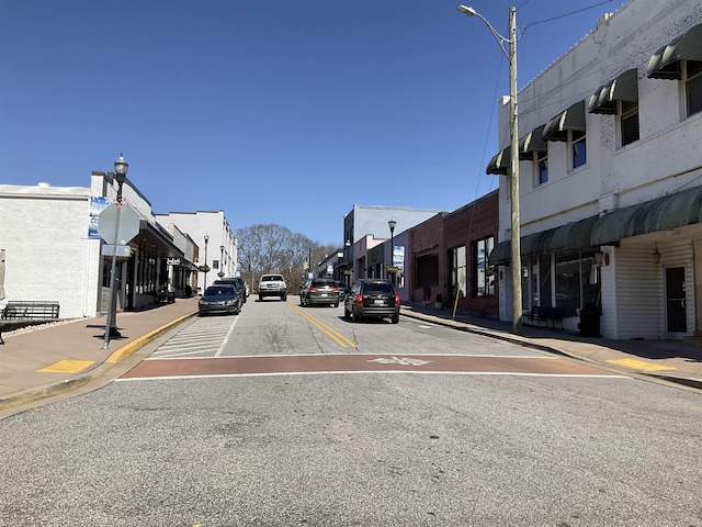 view of road with curbs, traffic signs, street lighting, and sidewalks