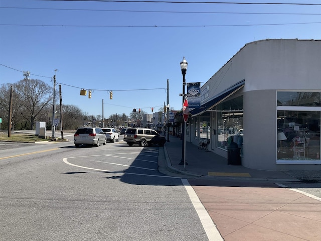 view of road with traffic signs, sidewalks, traffic lights, curbs, and street lighting