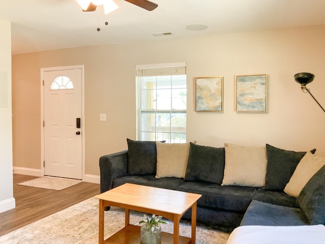 living area with visible vents, baseboards, wood finished floors, and a ceiling fan