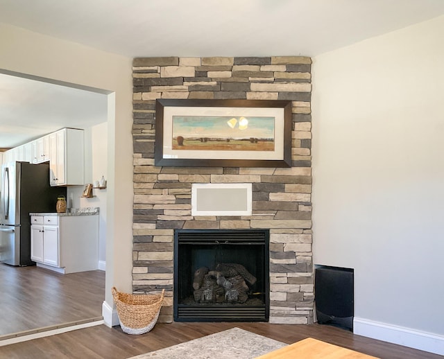 details featuring baseboards, wood finished floors, a fireplace, and freestanding refrigerator