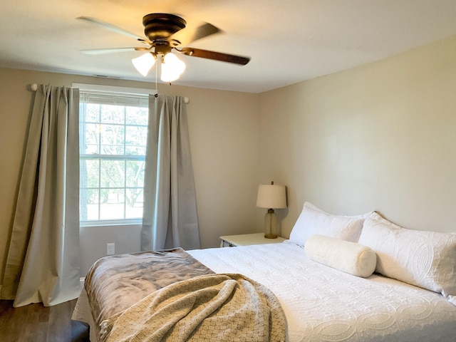 bedroom with dark wood-style floors, multiple windows, and ceiling fan