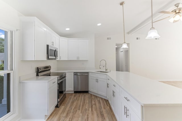 kitchen featuring light countertops, appliances with stainless steel finishes, a peninsula, white cabinetry, and a sink