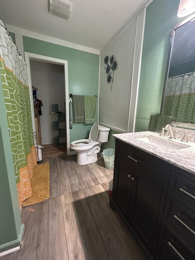 full bath featuring toilet, wood finished floors, vanity, and ornamental molding