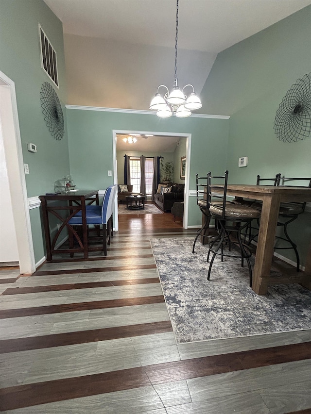 dining space featuring a notable chandelier, high vaulted ceiling, visible vents, and wood finished floors