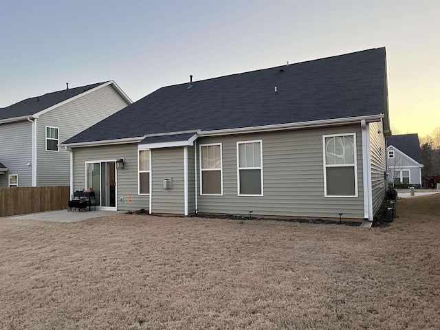 back of property at dusk with a patio and fence