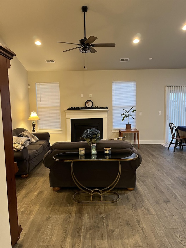 living area with dark wood finished floors, a ceiling fan, visible vents, and a fireplace