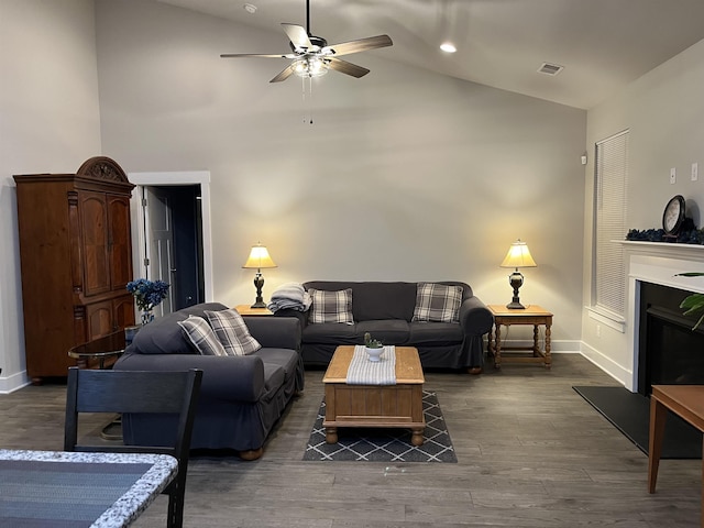 living area with visible vents, high vaulted ceiling, a ceiling fan, wood finished floors, and baseboards