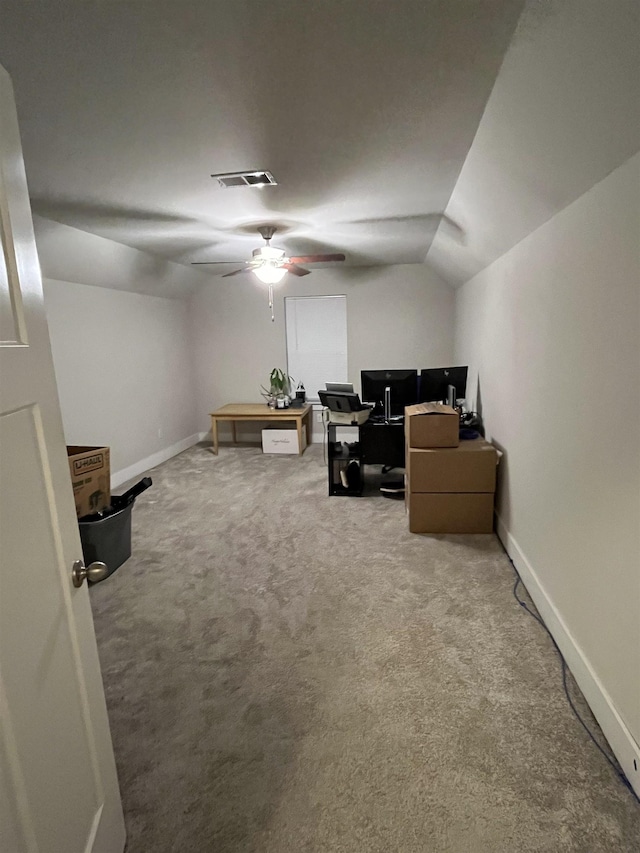 carpeted office space featuring vaulted ceiling, visible vents, baseboards, and ceiling fan