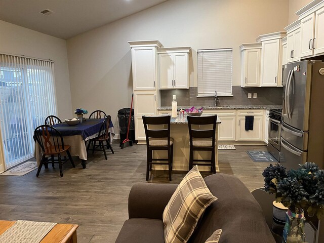 kitchen featuring a sink, light stone countertops, stainless steel appliances, white cabinetry, and dark wood-style flooring