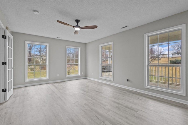 unfurnished room featuring visible vents, baseboards, a textured ceiling, and wood finished floors