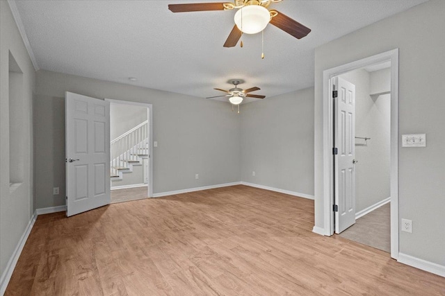 empty room featuring a textured ceiling, baseboards, and light wood-style floors