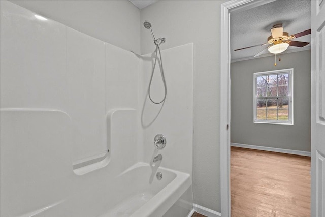 full bathroom featuring a ceiling fan, wood finished floors, baseboards, shower / washtub combination, and a textured ceiling