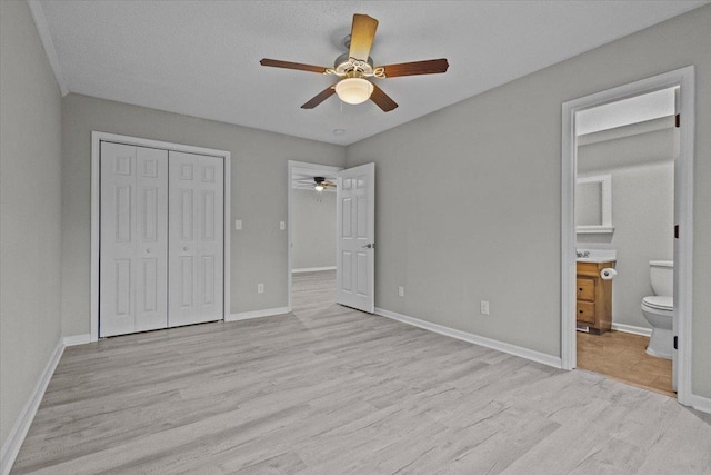 unfurnished bedroom featuring light wood-type flooring, baseboards, and a closet