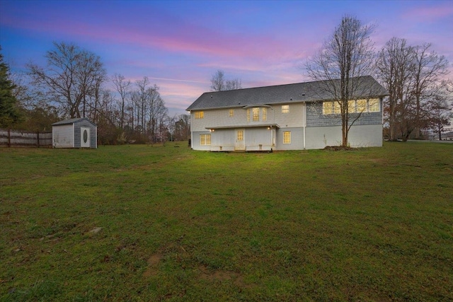 exterior space featuring an outbuilding, a lawn, a storage unit, and fence