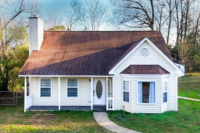 view of front facade with a chimney, a shingled roof, a front lawn, and fence