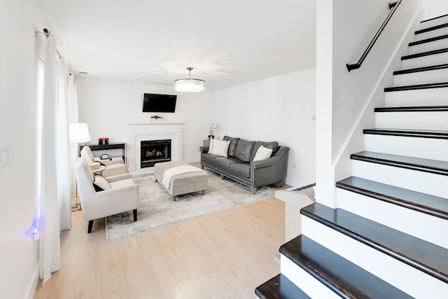 living area featuring a fireplace, stairs, and wood finished floors