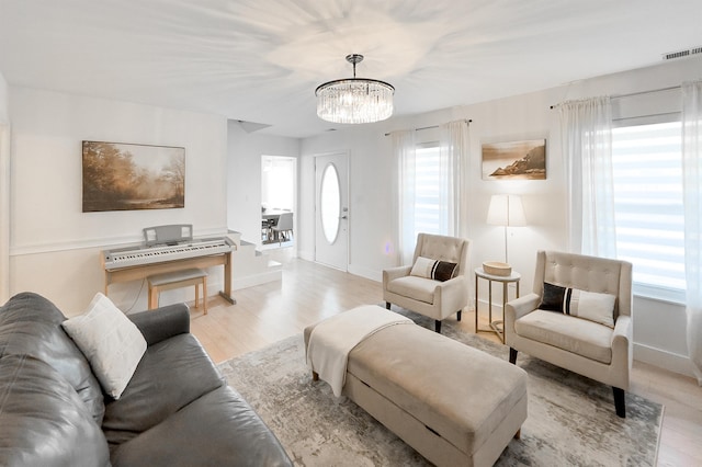 living area featuring a notable chandelier, a healthy amount of sunlight, and visible vents