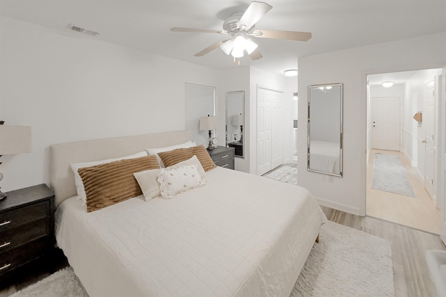 bedroom with visible vents, light wood-style flooring, a ceiling fan, connected bathroom, and baseboards