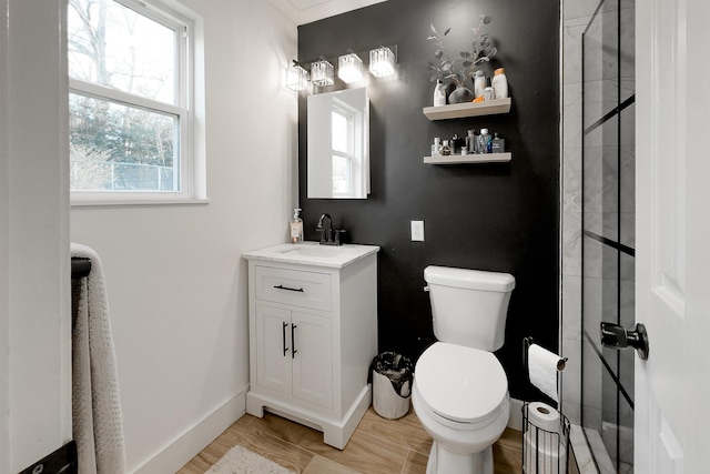 bathroom with baseboards, tiled shower, toilet, and vanity