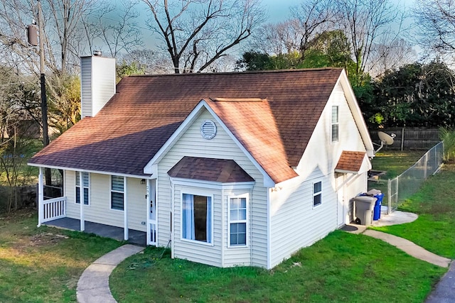 view of front of home with fence, a front yard, a chimney, and a shingled roof