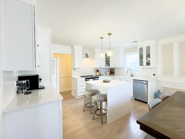 kitchen with light wood-type flooring, a kitchen bar, a kitchen island, white cabinets, and dishwasher