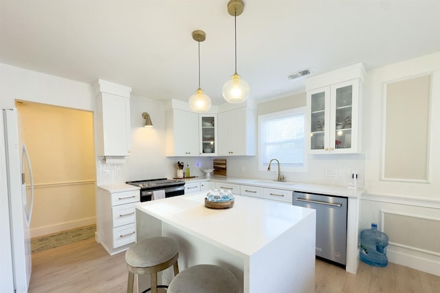 kitchen with light wood finished floors, visible vents, backsplash, stainless steel appliances, and a sink