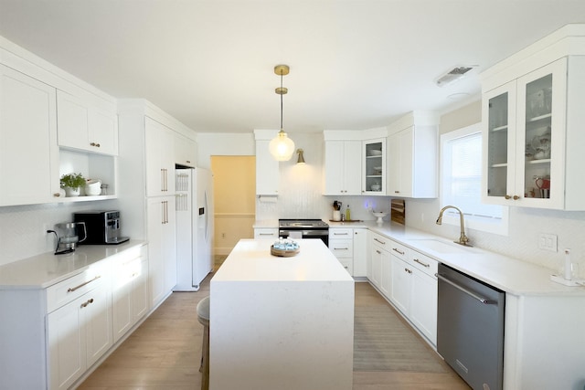 kitchen with visible vents, a kitchen island, light wood-type flooring, stainless steel appliances, and a sink