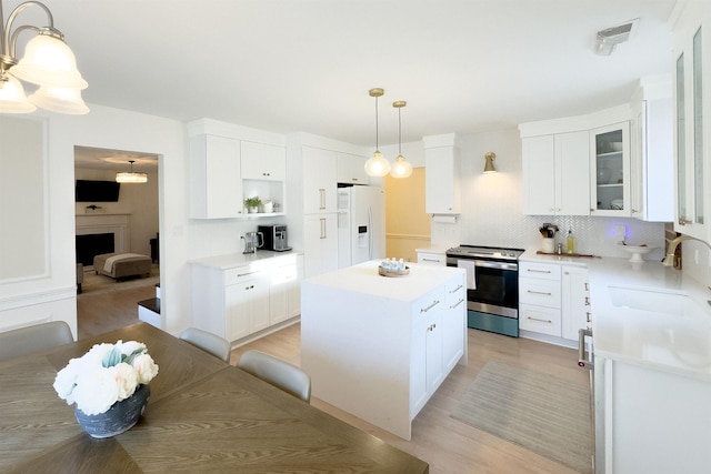 kitchen with a kitchen island, electric range, a sink, white fridge with ice dispenser, and tasteful backsplash