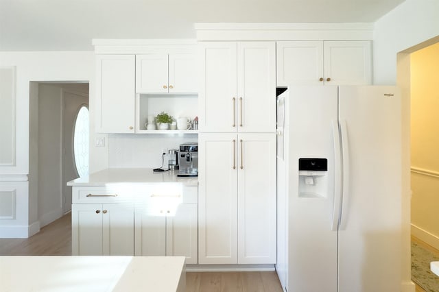 kitchen with backsplash, light countertops, white refrigerator with ice dispenser, white cabinetry, and open shelves