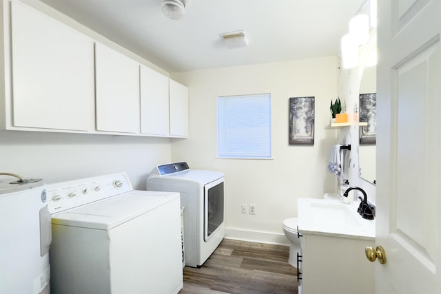 washroom featuring dark wood-type flooring, washing machine and dryer, water heater, laundry area, and a sink