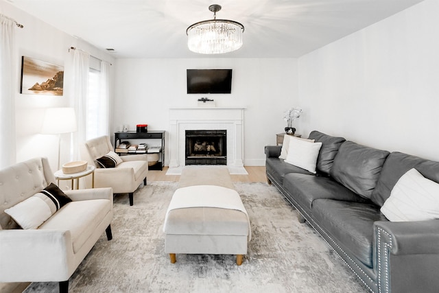 living room with a fireplace with flush hearth, light wood-style floors, and an inviting chandelier