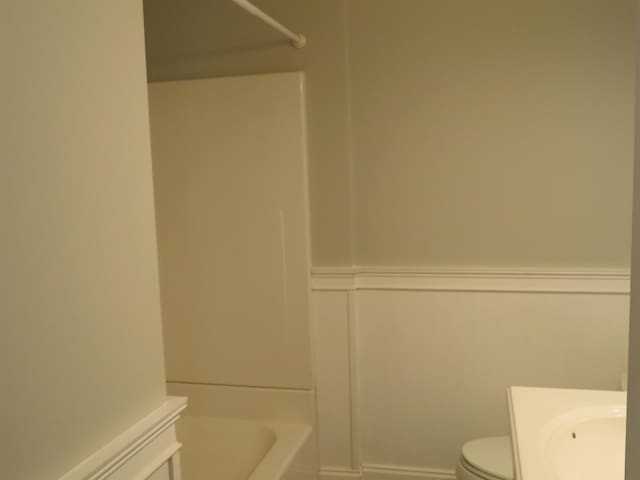 full bath with toilet, a tub, wainscoting, walk in shower, and vanity