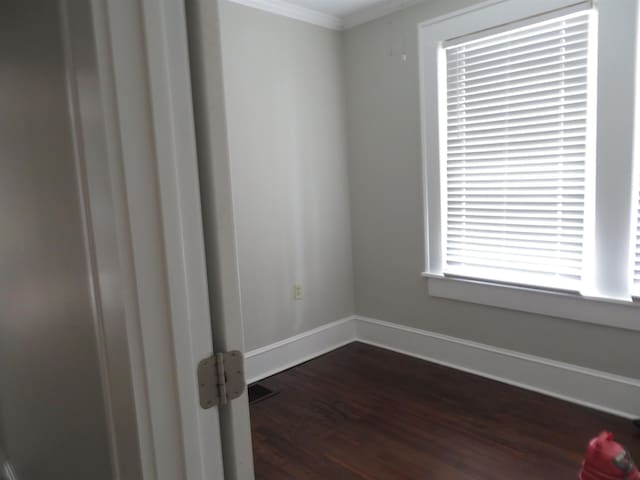 spare room featuring dark wood-type flooring, baseboards, and ornamental molding