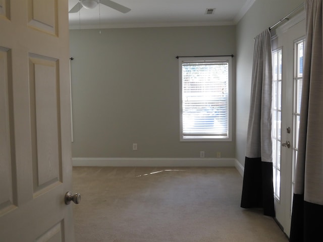 unfurnished room featuring visible vents, light carpet, crown molding, baseboards, and ceiling fan