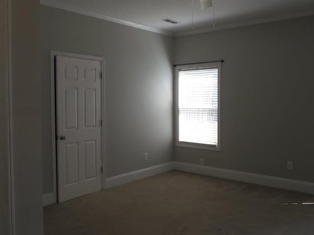 spare room featuring visible vents, carpet, baseboards, and ornamental molding