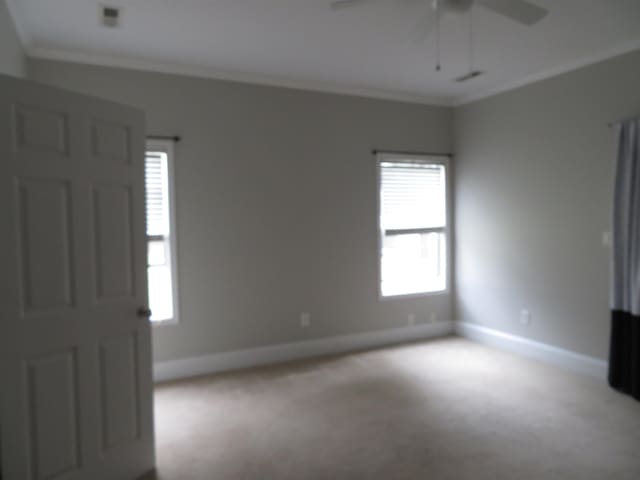 empty room featuring baseboards, crown molding, a ceiling fan, and carpet floors