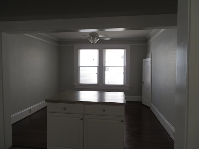 kitchen with a ceiling fan, baseboards, ornamental molding, dark wood-type flooring, and white cabinetry