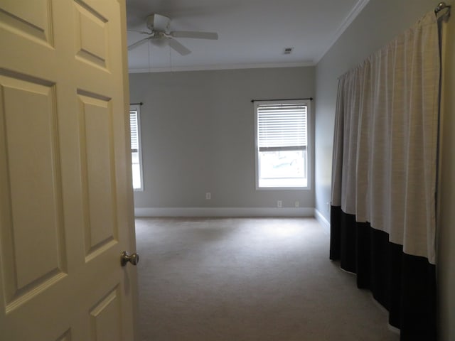 spare room featuring visible vents, crown molding, baseboards, light carpet, and a ceiling fan