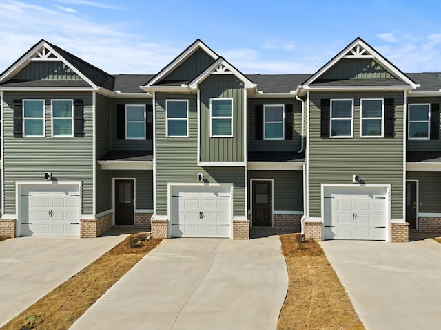 townhome / multi-family property with an attached garage, brick siding, board and batten siding, and driveway