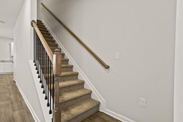 stairs featuring visible vents, baseboards, and wood finished floors