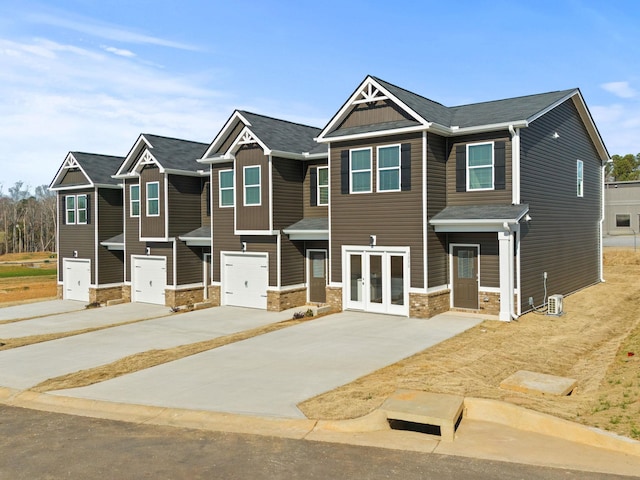 multi unit property with french doors, driveway, board and batten siding, and an attached garage