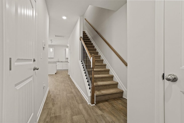 staircase with visible vents, recessed lighting, wood finished floors, and baseboards