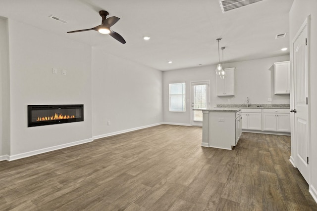 kitchen featuring visible vents, a glass covered fireplace, and dark wood-style flooring