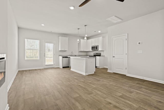 kitchen featuring stainless steel appliances, wood finished floors, a ceiling fan, and white cabinetry