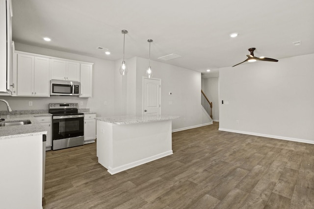 kitchen featuring dark wood-type flooring, a sink, a center island, stainless steel appliances, and white cabinets