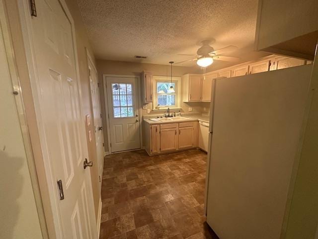 kitchen with a ceiling fan, a sink, decorative light fixtures, freestanding refrigerator, and light countertops