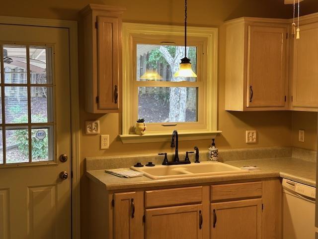 kitchen featuring dishwasher, pendant lighting, light countertops, and a sink