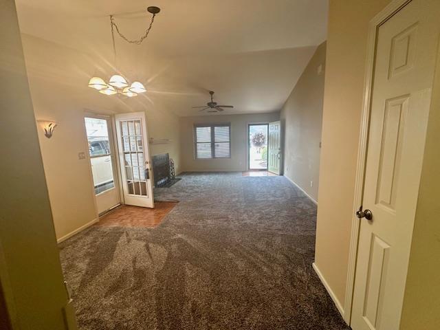 unfurnished living room with carpet flooring, ceiling fan with notable chandelier, french doors, and baseboards