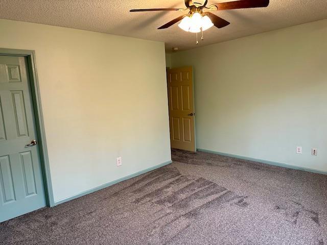 carpeted empty room with baseboards, a textured ceiling, and a ceiling fan