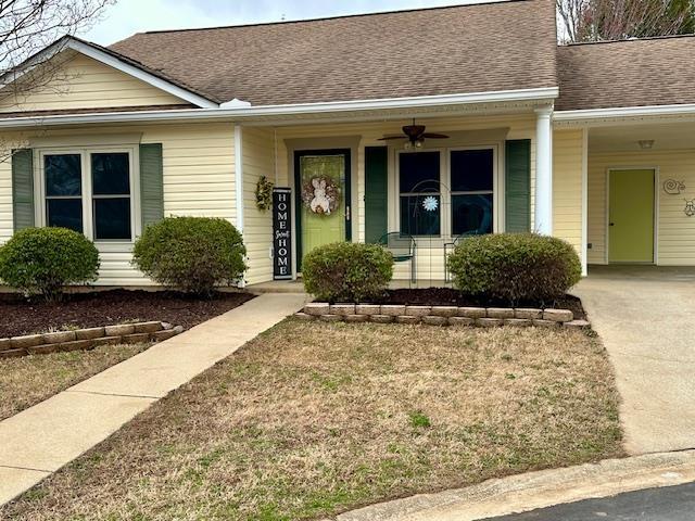 single story home with an attached carport, covered porch, concrete driveway, and a shingled roof